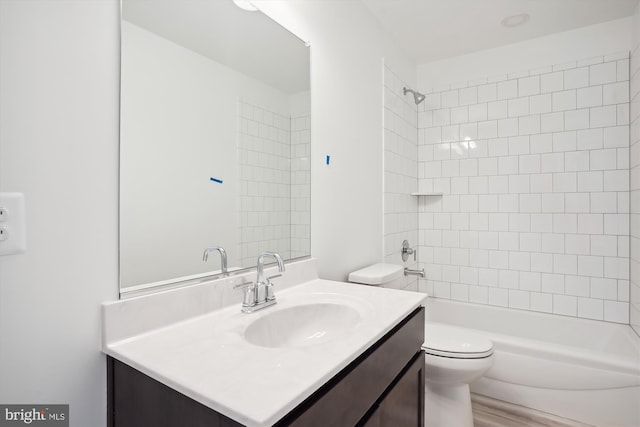 full bathroom featuring tiled shower / bath combo, toilet, and vanity