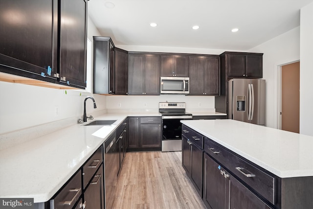 kitchen with a center island, light wood-type flooring, appliances with stainless steel finishes, sink, and dark brown cabinetry