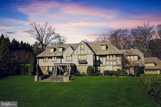 back house at dusk featuring a yard