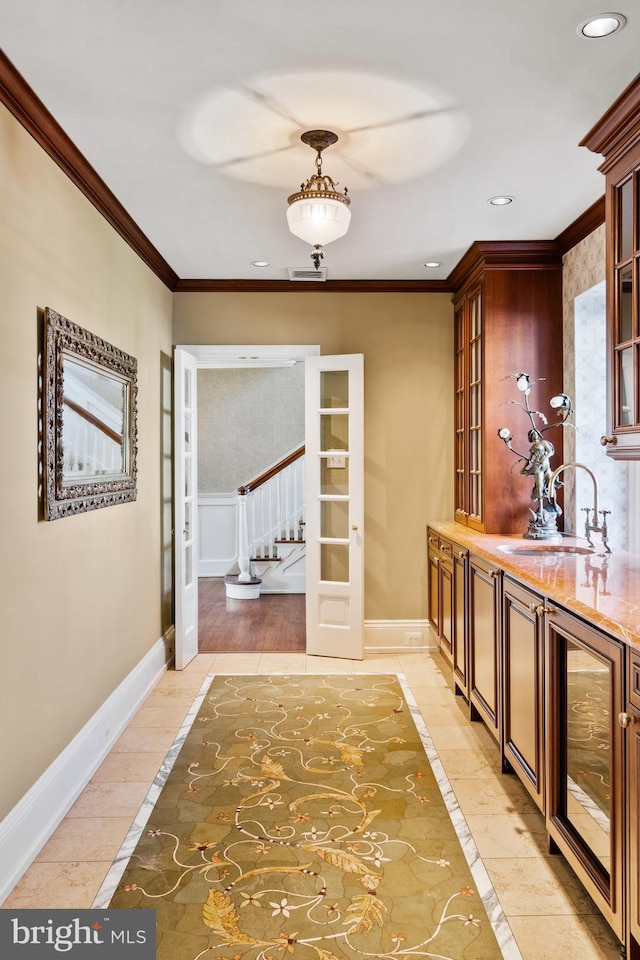 interior space with decorative light fixtures, sink, crown molding, and light wood-type flooring