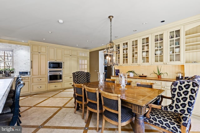 dining area featuring a notable chandelier, light tile floors, and ornamental molding