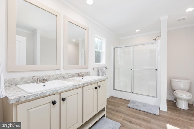 bathroom with wood-type flooring, crown molding, toilet, and dual bowl vanity