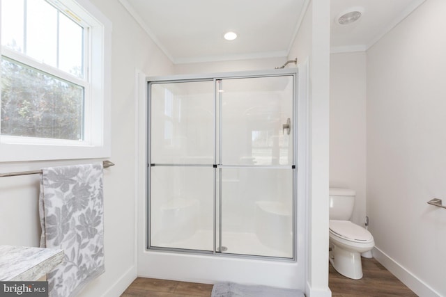 bathroom featuring hardwood / wood-style floors, crown molding, toilet, and a shower with shower door