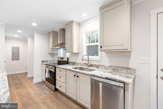 kitchen with wall chimney exhaust hood, light wood-type flooring, appliances with stainless steel finishes, sink, and light stone counters