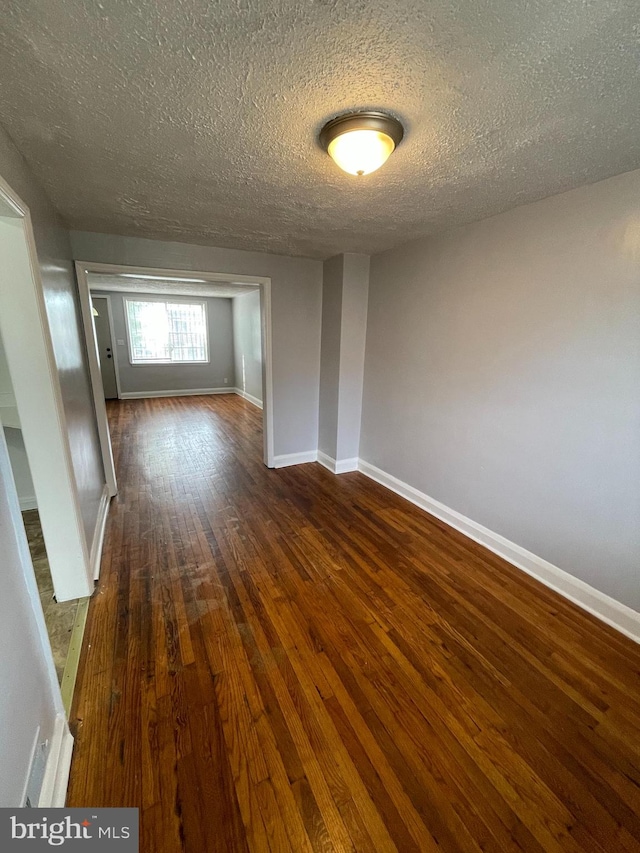 empty room with a textured ceiling and dark wood-type flooring