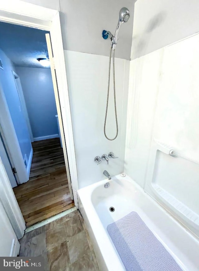 bathroom featuring hardwood / wood-style floors and  shower combination