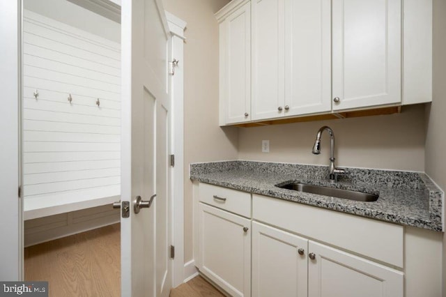 kitchen with light stone counters, sink, light hardwood / wood-style floors, and white cabinets