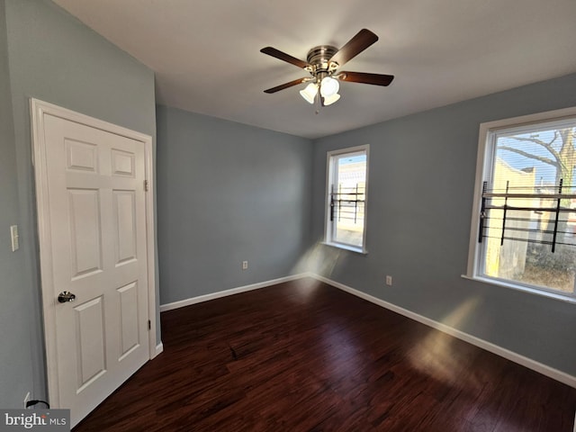 unfurnished room with a wealth of natural light, ceiling fan, and dark wood-type flooring