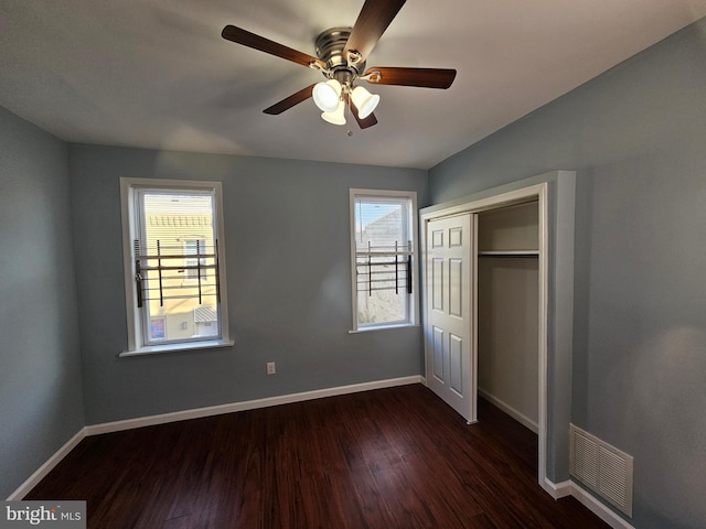 unfurnished bedroom with dark hardwood / wood-style flooring, a closet, and ceiling fan