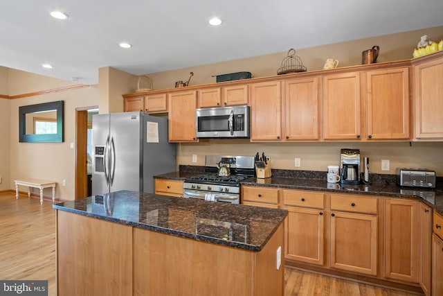 kitchen featuring a kitchen island, dark stone countertops, stainless steel appliances, and light wood-type flooring