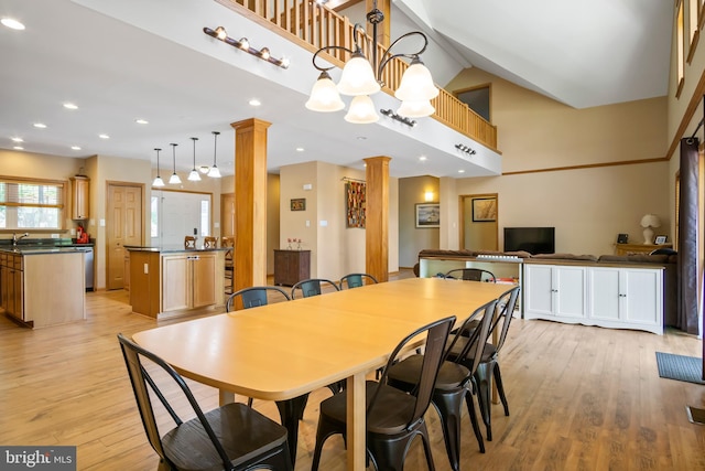 dining space featuring light hardwood / wood-style flooring, sink, a towering ceiling, and decorative columns