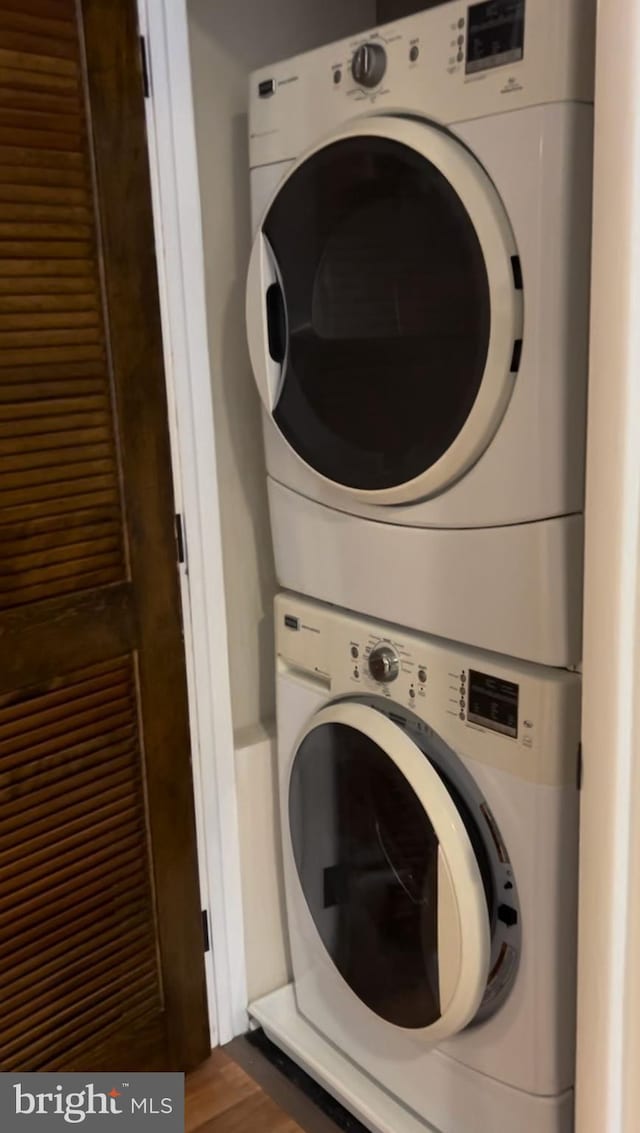 laundry area featuring stacked washing maching and dryer and wood-type flooring