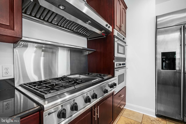 kitchen with appliances with stainless steel finishes, fume extractor, and light tile floors