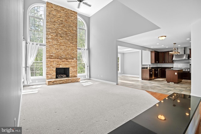 unfurnished living room featuring light colored carpet, a high ceiling, crown molding, and a fireplace