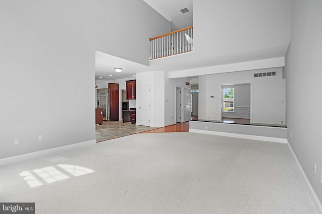 unfurnished living room with a towering ceiling and carpet floors