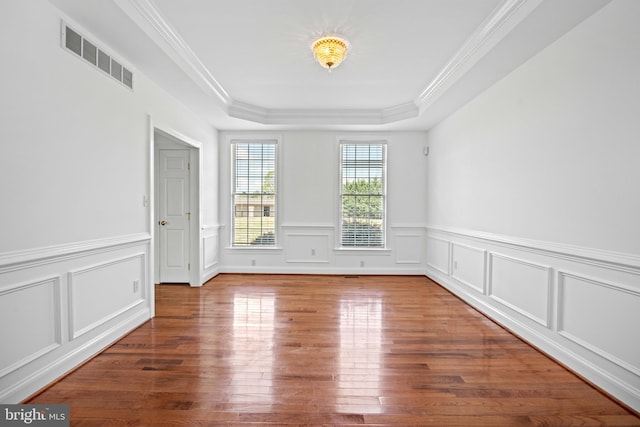 empty room featuring crown molding, dark hardwood / wood-style floors, and a raised ceiling