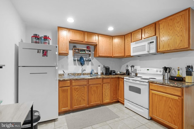 kitchen with light tile floors, dark stone counters, white appliances, and sink