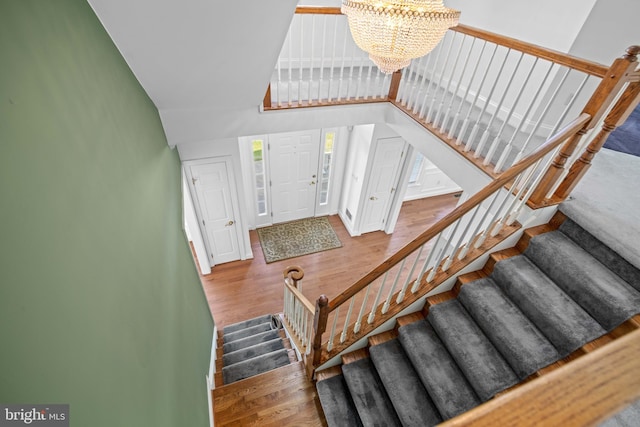 stairs featuring hardwood / wood-style flooring and a chandelier