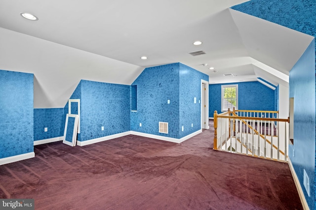 bonus room with dark colored carpet and vaulted ceiling