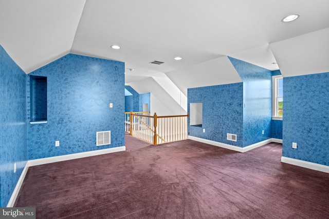 bonus room with lofted ceiling and dark colored carpet