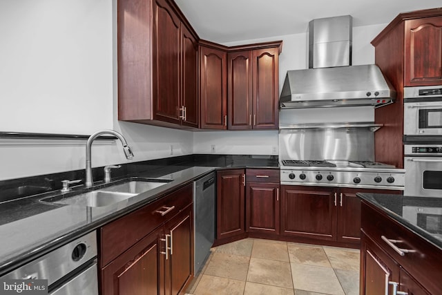 kitchen featuring light tile floors, sink, wall chimney range hood, stainless steel appliances, and dark stone countertops