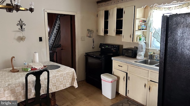 kitchen with sink, black appliances, dark hardwood / wood-style floors, and an inviting chandelier