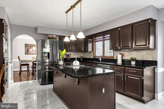 kitchen with a center island, appliances with stainless steel finishes, light tile patterned flooring, backsplash, and decorative light fixtures