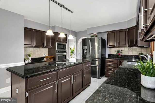 kitchen with tasteful backsplash, dark brown cabinets, stainless steel appliances, and a kitchen island