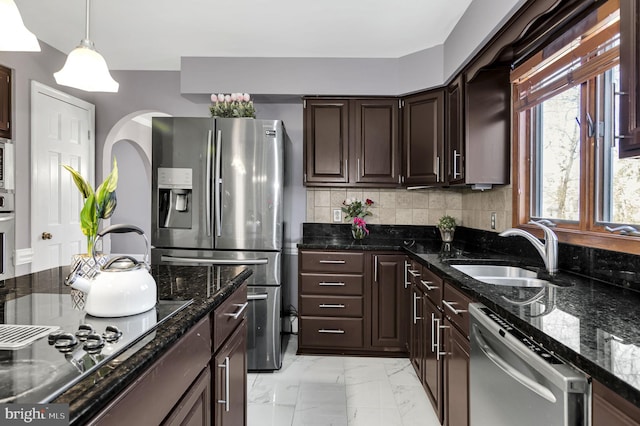 kitchen featuring dark stone countertops, appliances with stainless steel finishes, backsplash, sink, and light tile patterned flooring