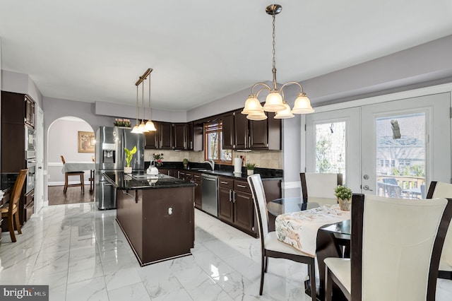 kitchen featuring tasteful backsplash, light wood-type flooring, pendant lighting, appliances with stainless steel finishes, and a kitchen island