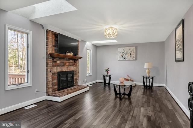 living area with a fireplace, dark wood-type flooring, a wealth of natural light, and a skylight