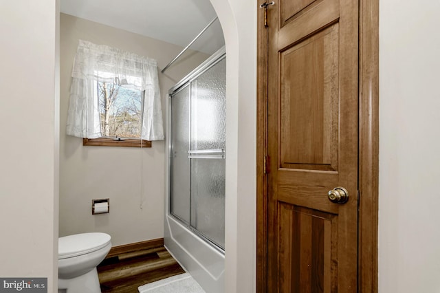 bathroom featuring bath / shower combo with glass door, wood-type flooring, and toilet