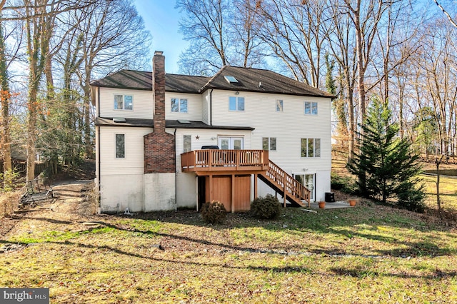 back of property featuring a wooden deck and a lawn