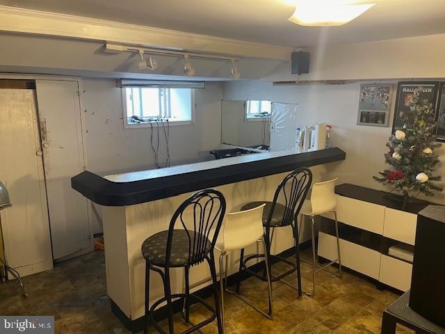 bar with rail lighting and dark tile flooring