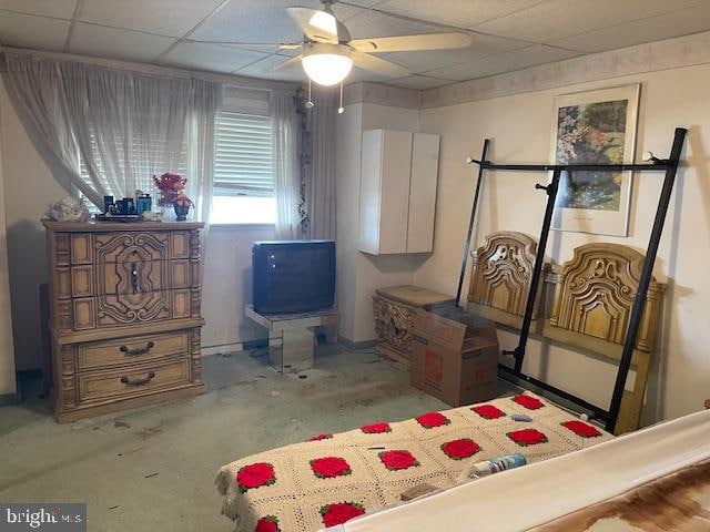 bedroom featuring a paneled ceiling, concrete flooring, and ceiling fan