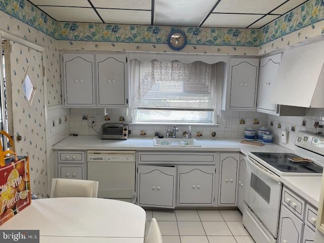 kitchen with white appliances, gray cabinetry, light tile floors, sink, and tasteful backsplash