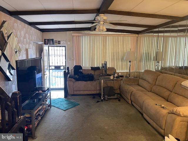 living room featuring ceiling fan and vaulted ceiling with beams