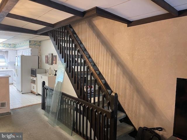 staircase with a paneled ceiling and light tile floors