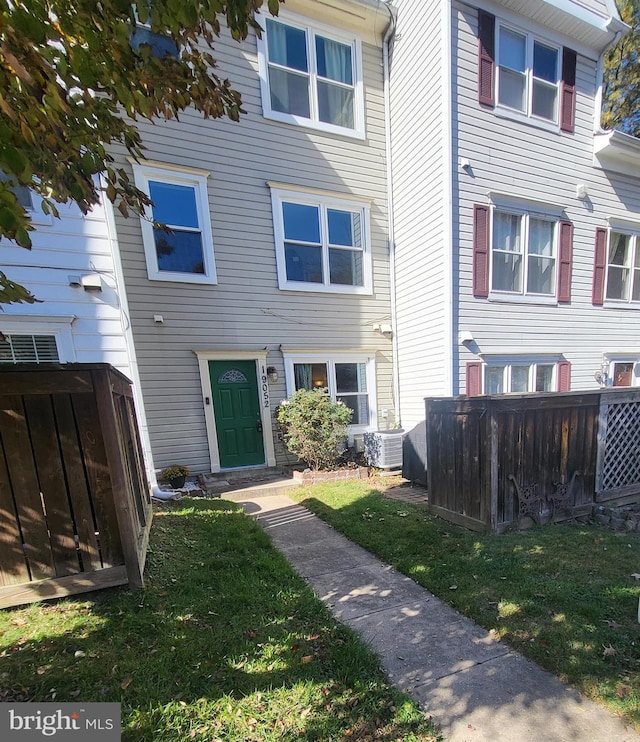 view of front of house with cooling unit and a front lawn