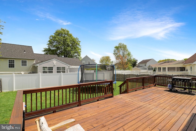 deck featuring a trampoline and a lawn