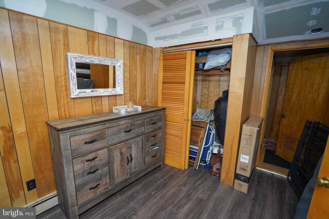 bedroom with a baseboard heating unit, dark wood-type flooring, wooden walls, and coffered ceiling