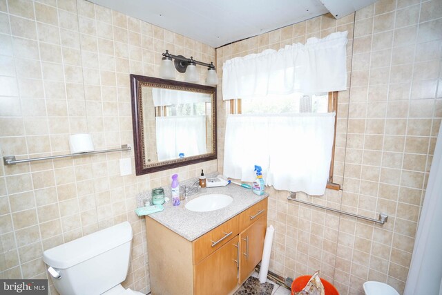 bathroom featuring vanity, a wealth of natural light, toilet, and tile walls