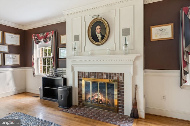 living room featuring ornamental molding, hardwood / wood-style flooring, and a brick fireplace