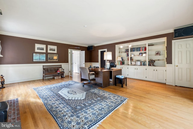 home office featuring built in shelves, ornamental molding, and light hardwood / wood-style floors