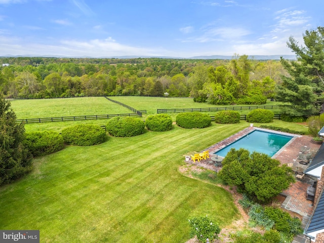 view of pool with a rural view and a yard