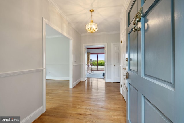 entryway with an inviting chandelier, crown molding, and light wood-type flooring