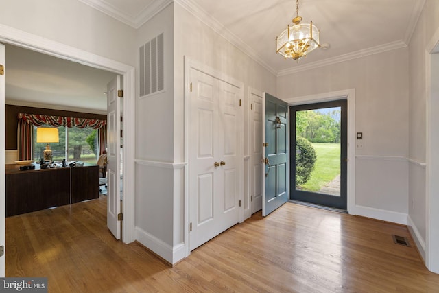 foyer entrance featuring a notable chandelier, crown molding, and light wood-type flooring