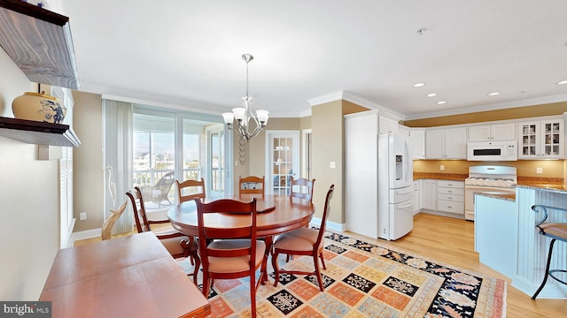 dining space with light wood-type flooring, crown molding, and a notable chandelier