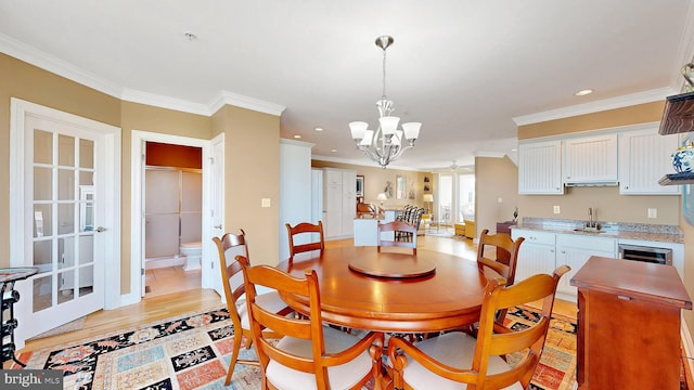 dining room featuring a chandelier, light wood-type flooring, ornamental molding, and sink