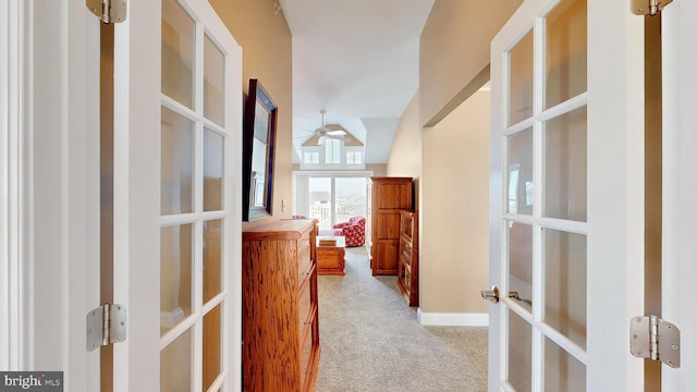 corridor with a towering ceiling, light carpet, and french doors